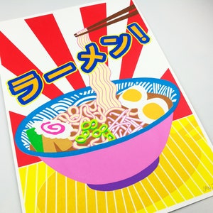 Pu&ograve; includere: Una ciotola rosa di ramen con noodles, cipolle verdi e due uova. La ciotola &egrave; su uno sfondo a strisce giallo e bianco con la parola "Ramen" in caratteri giapponesi.