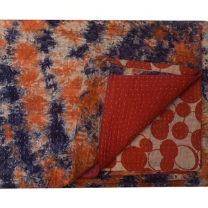 May include: A reversible kantha quilt with a tie-dye pattern on one side and a red and white circle pattern on the other side.