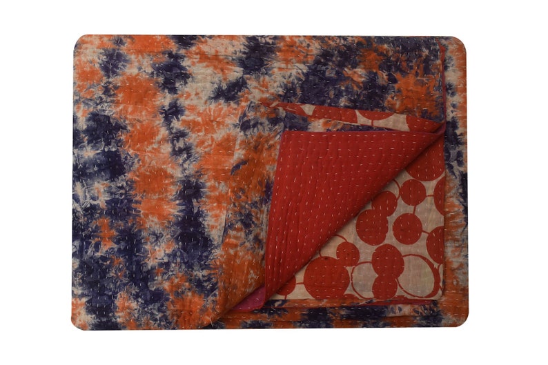 May include: A reversible kantha quilt with a tie-dye pattern on one side and a red and white circle pattern on the other side.