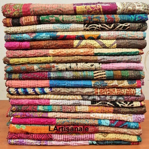 May include: A stack of colorful kantha quilts made from recycled saris. The quilts are layered in a variety of patterns and colors, including pink, blue, green, yellow, and orange. The quilts are hand-stitched and have a unique, vintage look.