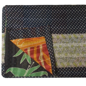 K&ouml;nnte beinhalten: Eine schwarze Kantha-Steppdecke mit einem wei&szlig;en Tupfenmuster, einem gr&uuml;nen Blumenmuster und einem mehrfarbigen Streifenmuster. Die Decke ist in der Mitte gefaltet und die verschiedenen Muster sind sichtbar.