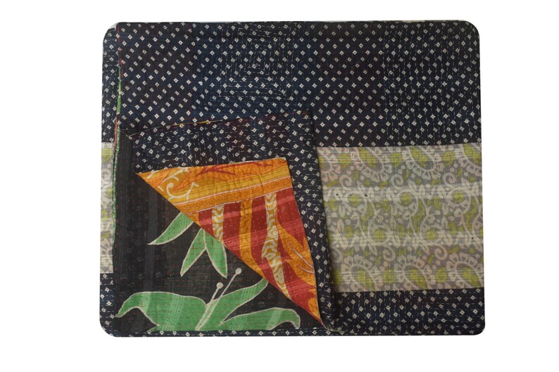 K&ouml;nnte beinhalten: Eine schwarze Kantha-Steppdecke mit einem wei&szlig;en Tupfenmuster, einem gr&uuml;nen Blumenmuster und einem mehrfarbigen Streifenmuster. Die Decke ist in der Mitte gefaltet und die verschiedenen Muster sind sichtbar.