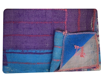 May include: A handmade, reversible quilt with a patchwork design. The quilt features a color scheme of purple, blue, and red. The quilt is made of fabric and has a textured appearance. The quilt is folded over, revealing a contrasting blue and white pattern.