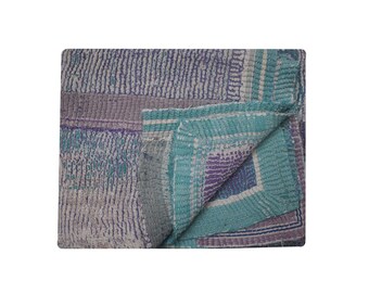 May include: A kantha quilt with a patchwork design in shades of purple, blue, and white. The quilt is folded in half, revealing the intricate stitching and layering of the fabric.