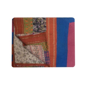 Pode incluir: Uma colcha de retalhos com uma variedade de cores e padr&otilde;es, incluindo vermelho, azul, verde e marrom. A colcha est&aacute; dobrada ao meio, revelando o lado de tr&aacute;s, que &eacute; branco s&oacute;lido com um padr&atilde;o floral.