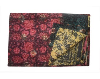 May include: A multi-colored kantha quilt with a floral pattern. The quilt is made of recycled saris and is hand-stitched. The quilt is folded in half and is lying on a white background.