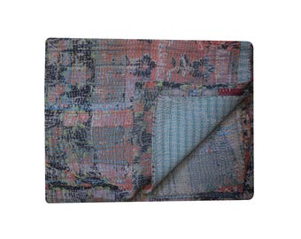 May include: A kantha quilt with a patchwork design featuring a mix of blue, pink, and green colors. The quilt is folded in half, revealing a light blue and white striped pattern on the underside.