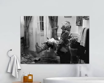 May include: Monochrome framed print depicting a person laughing on a toilet. The person is wearing a shirt and boots. The background shows a window with curtains and a towel rail.