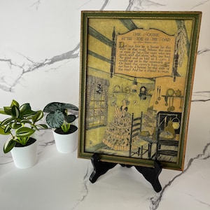 Könnte beinhalten: Ein Vintage-Rahmenbild mit vergilbtem Hintergrund und grünem Rahmen. Der Druck zeigt ein Gedicht mit dem Titel "He Ouse By The Side Of He Oad" mit einer Illustration einer Frau in einem gelben Kleid, die in einem Raum mit einem Kamin und einem Fenster steht.