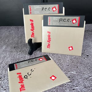 Puede incluir: Tres disquetes vintage para la computadora Apple II. Los disquetes están etiquetados con "The Apple II" y tienen el texto "P.C.C." escrito en ellos. Los disquetes están en su embalaje original.