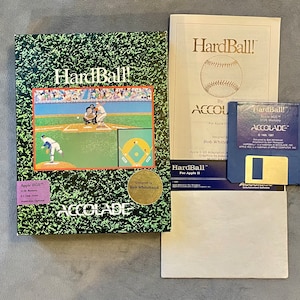 May include: A vintage "HardBall!" computer game for Apple II, featuring a baseball scene on the box. Includes a blue 3.5" floppy disk, manual, and box with the Accolade logo. The box has a green grass-like pattern.