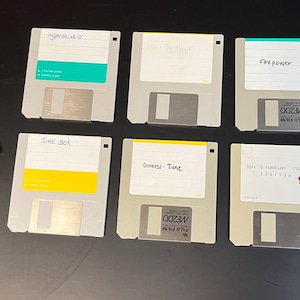 Puede incluir: Seis disquetes de 3,5 pulgadas con etiquetas escritas a mano. Las etiquetas incluyen "Hyperstudio", "SiKE BOX", "Diversi-Tune", "Scottie Mack", "Firepower" y "Vol. 1 "Knowledge" Science 12/22/86".