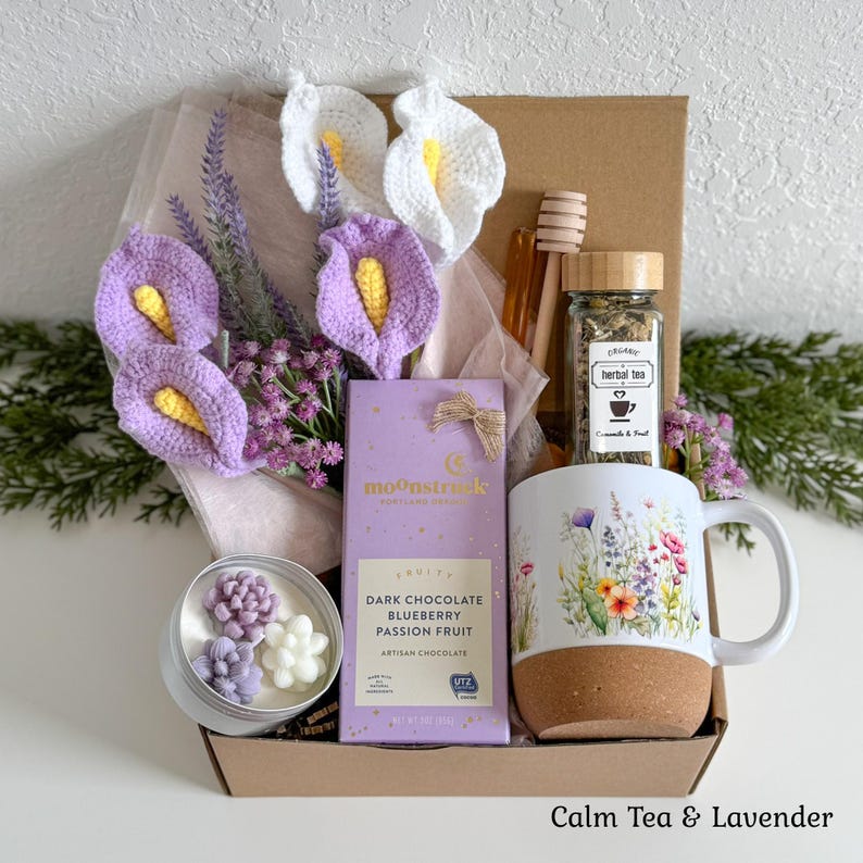 Pu&ograve; includere: Una confezione regalo contenente una tavoletta di cioccolato fondente Moonstruck, una tazza con stampa floreale e base in sughero, un barattolo di tisana, un mestolo per miele in legno, una candela con cera a forma di succulente e calle.