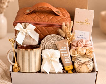 Può includere: Una confezione regalo contenente una trousse trapuntata marrone con manico, una tazza in ceramica a coste con cucchiaio dorato, un sacchetto con nastro bianco, una crema mani al latte, una candela, due elastici e una tavoletta di cioccolato.