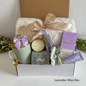 Pu&ograve; includere: Una confezione regalo contenente una coperta in maglia color crema con nastro dorato, una tazza verde chiaro con cucchiaio dorato, un sacchetto di juta con fiocco color lavanda, una candela, calzini grigi, cioccolato Moonstruck, due elastici e un tubetto lavanda e salvia.