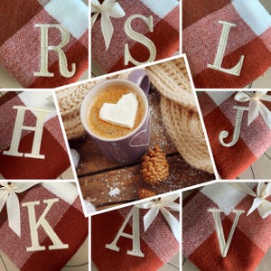 May include: A set of 9 personalized fleece blankets with a red and white plaid pattern. Each blanket features a different letter embroidered in white on the red plaid. The letters are R, S, L, H, J, K, A, V.