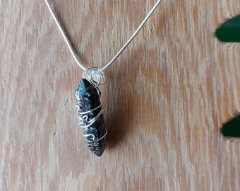 May include: A silver chain necklace with a black and white stone pendant wrapped in silver wire.