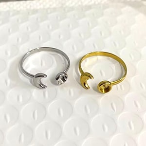 Puede incluir: Dos anillos ajustables con un diseño de media luna. Un anillo es plateado y el otro es dorado.