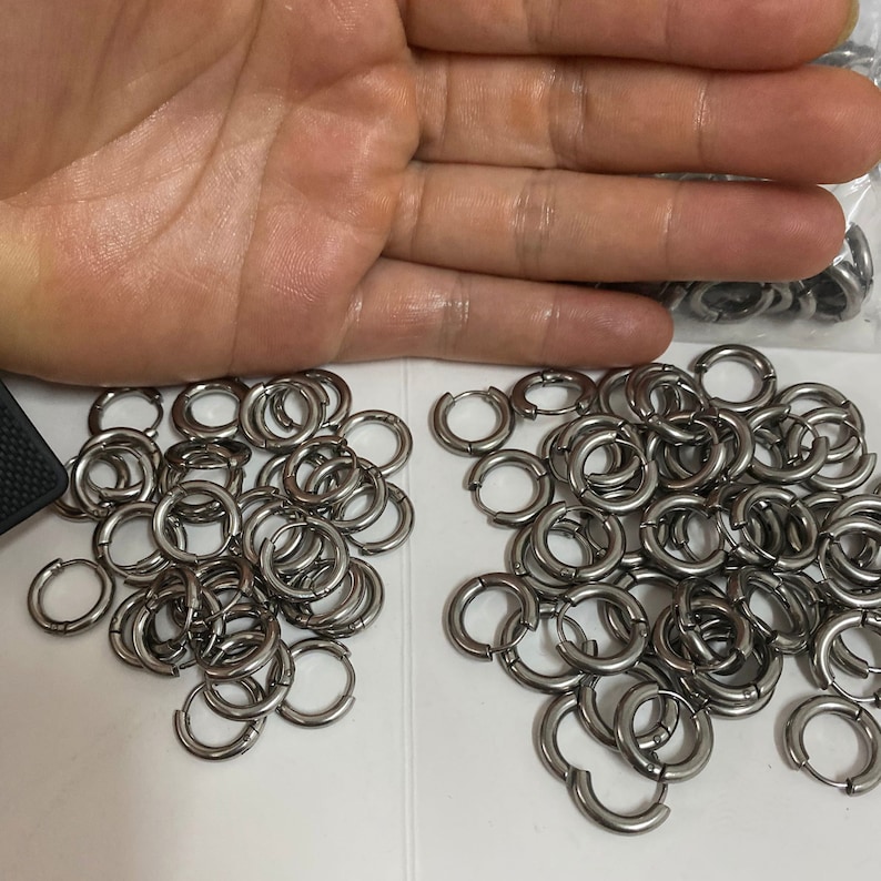 May include: A large pile of silver hoop earrings. The earrings are all the same size and are made of a shiny metal.