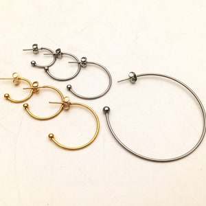 Op de afbeelding: Drie paar creolen in verschillende maten. De oorbellen zijn gemaakt van metaal en hebben een glanzende afwerking. Het kleinste paar is goud, het middelste paar is zilver en het grootste paar is zilver.
