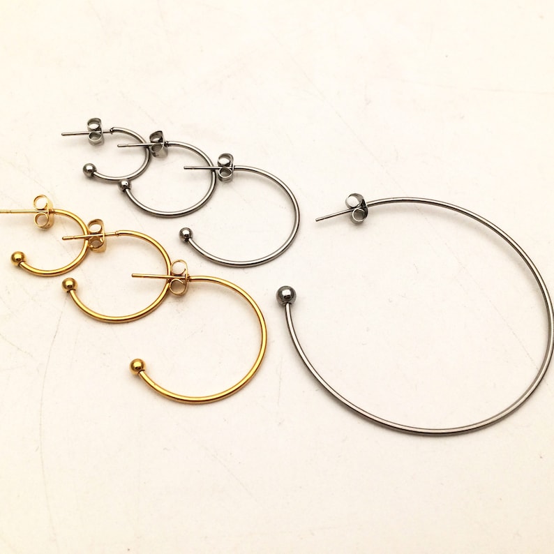 Op de afbeelding: Drie paar creolen in verschillende maten. De oorbellen zijn gemaakt van metaal en hebben een glanzende afwerking. Het kleinste paar is goud, het middelste paar is zilver en het grootste paar is zilver.