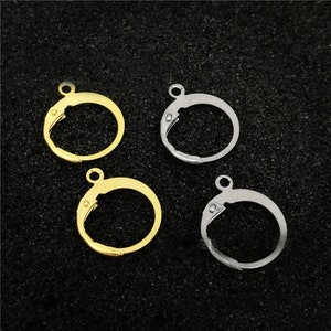 Op de afbeelding: Vier oorringen, twee gouden en twee zilveren, met een veerclip sluiting.