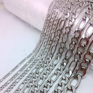 Può includere: Un set di collane a catena argentate di diverse larghezze e lunghezze. Le catene sono in metallo lucido e hanno un design classico a maglie.