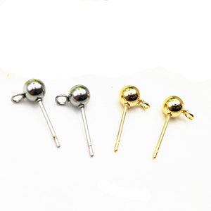 May include: Four earring posts with a small ball at the top and a loop for attaching jewelry. Two posts are silver and two are gold.