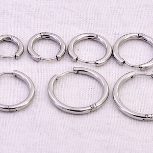 May include: Six silver hoop earrings of different sizes. The earrings are made of metal and have a hinged clasp.