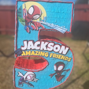 Może przedstawiać: Niebieska i czerwona pi&ntilde;ata w kształcie cyfry 5. Na g&oacute;rze znajduje się postać Spidermana, a na dole dwie inne postacie Spidermana. Pi&ntilde;ata ma napis "Jackson and his Amazing Friends".