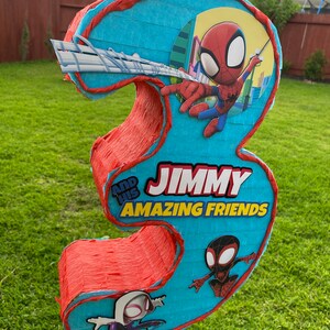 Może przedstawiać: Niebiesko-czerwona pi&ntilde;ata w kształcie cyfry trzy z motywem Spidermana. Pi&ntilde;ata ma napis "Jimmy and his Amazing Friends".