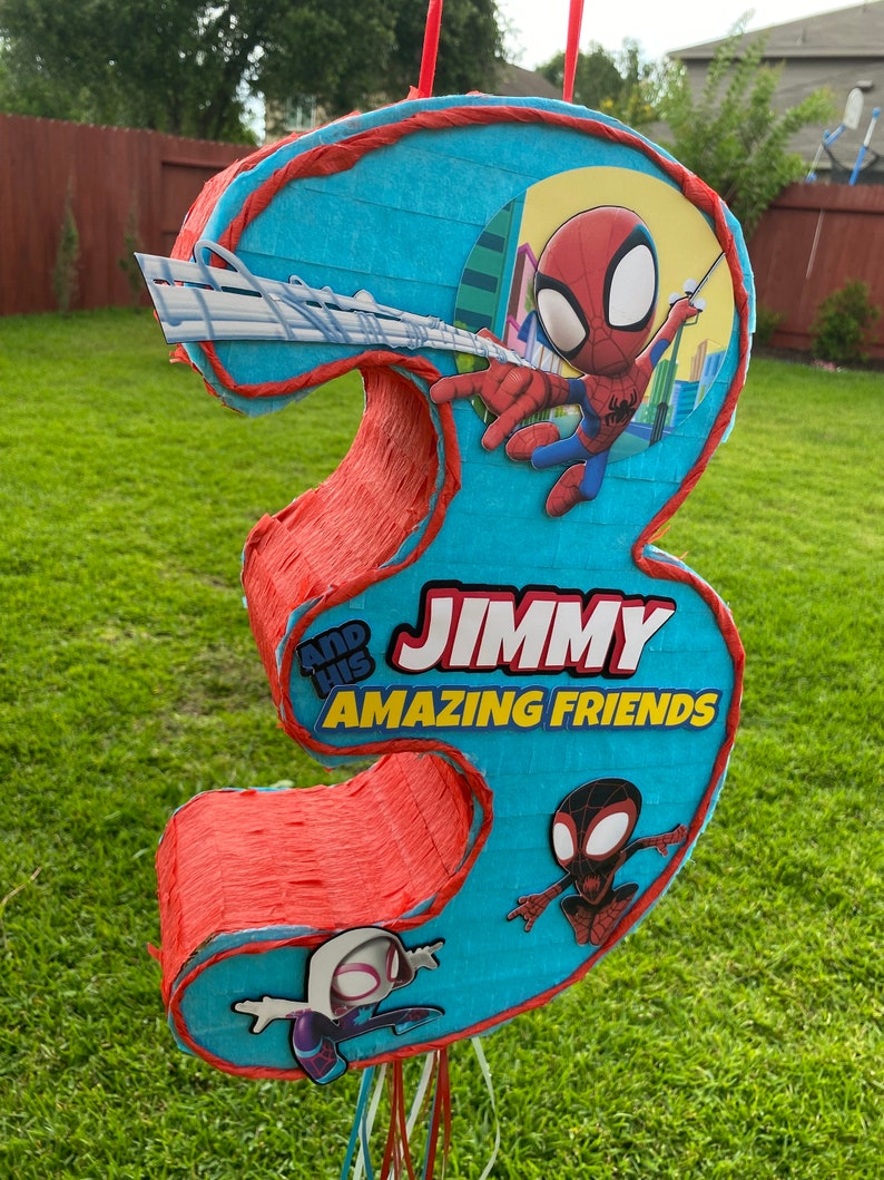 Może przedstawiać: Niebiesko-czerwona pi&ntilde;ata w kształcie cyfry trzy z motywem Spidermana. Pi&ntilde;ata ma napis "Jimmy and his Amazing Friends".