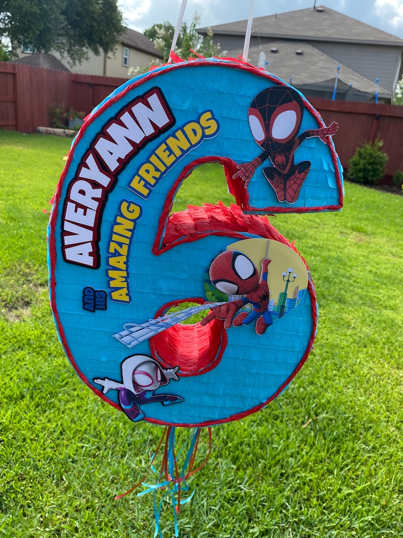 Może przedstawiać: Niebiesko-czerwona pi&ntilde;ata w kształcie sz&oacute;stki z motywem Spidermana. Na g&oacute;rze znajduje się napis "Averyann and His Amazing Friends".