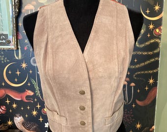 May include: A light brown suede vest with a V-neck and five button closures. The vest has two pockets on the front.