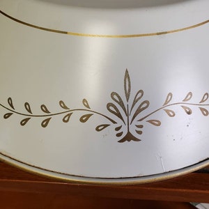 K&ouml;nnte beinhalten: Wei&szlig;e Metall-Tortenplatte mit goldfarbenem Rand und einem goldenen Blattdesign am Rand.