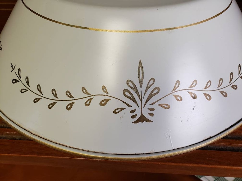 K&ouml;nnte beinhalten: Wei&szlig;e Metall-Tortenplatte mit goldfarbenem Rand und einem goldenen Blattdesign am Rand.