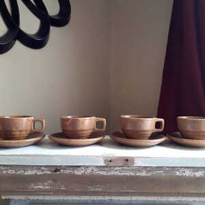 May include: Four brown ceramic teacups and saucers. The cups and saucers have a mottled brown glaze.