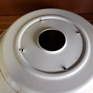 K&ouml;nnte beinhalten: Wei&szlig;e Metall-Deckenleuchte mit rundem, dekorativem Design. Die Leuchte hat ein zentrales Loch f&uuml;r eine Gl&uuml;hbirne und vier kleine L&ouml;cher am Rand.