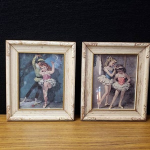 May include: Two framed vintage prints of young ballerinas in white tutus. The print on the left shows a girl and boy dancing together. The print on the right shows two girls standing together.