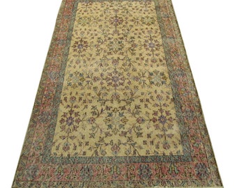 May include: A vintage rug with a floral pattern in shades of pink, purple, and blue on a cream background. The rug has a border with a repeating pattern in shades of green, pink, and blue.