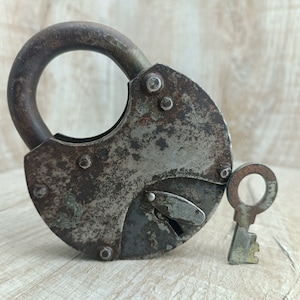 May include: A vintage padlock with a key. The padlock is made of metal and has a rusty patina. The key is also made of metal and has a simple design.