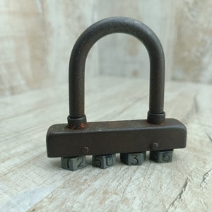May include: A rusty metal padlock with a combination lock. The lock has five numbered dials with the numbers 2, 5, 0, 3, and 6.