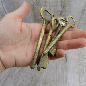 May include: A set of four antique brass keys with intricate designs. The keys are worn and have a patina finish, suggesting they are old and well-used.