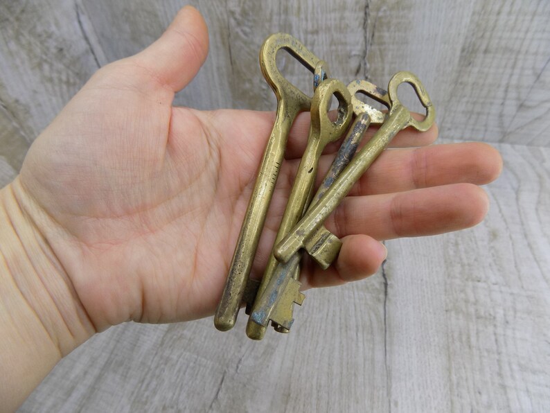 May include: A set of four antique brass keys with intricate designs. The keys are worn and have a patina finish, suggesting they are old and well-used.