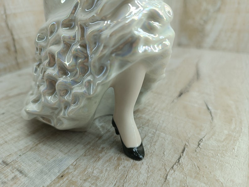 K&ouml;nnte beinhalten: Eine Porzellanfigur einer Frau in einem wei&szlig;en Kleid mit einem R&uuml;schenrock und schwarzen Schuhen.