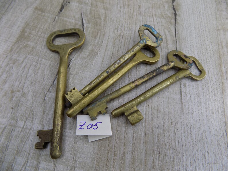 May include: Five antique brass keys with worn edges and a small white tag with the number "205" written in blue ink.