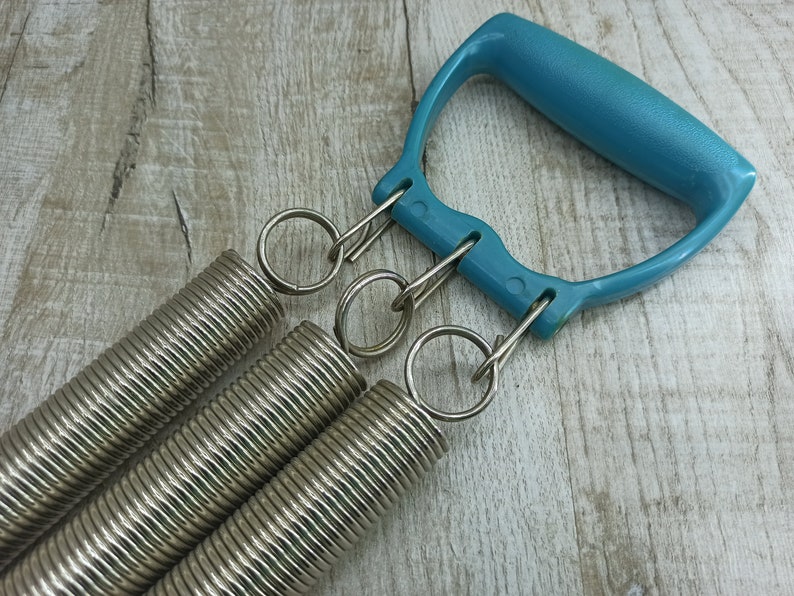 May include: A blue plastic handle with three silver spring coils attached. The coils are connected to the handle with silver rings.