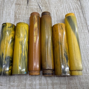 Może przedstawiać: Sześć żółtych i czarnych marmurowych prętów z tworzywa sztucznego, niektóre z brązowym odcieniem.