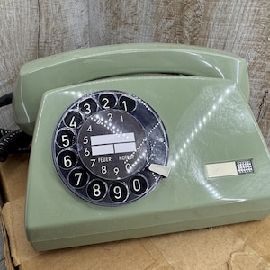 May include: A vintage green rotary dial phone with a black dial and a white label that says "Feuer Notruf".