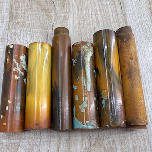 May include: Six different coloured, cylindrical, resin pen blanks. The blanks are all approximately 10 inches long and have a variety of patterns and colours, including brown, yellow, and blue.